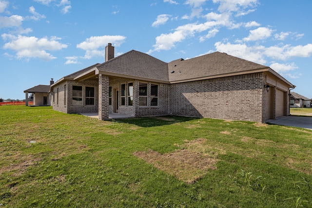 rear view of property featuring a garage and a yard