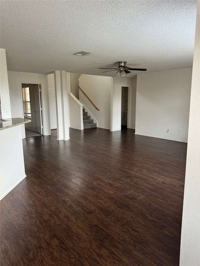 unfurnished living room featuring ceiling fan, dark hardwood / wood-style flooring, and a textured ceiling