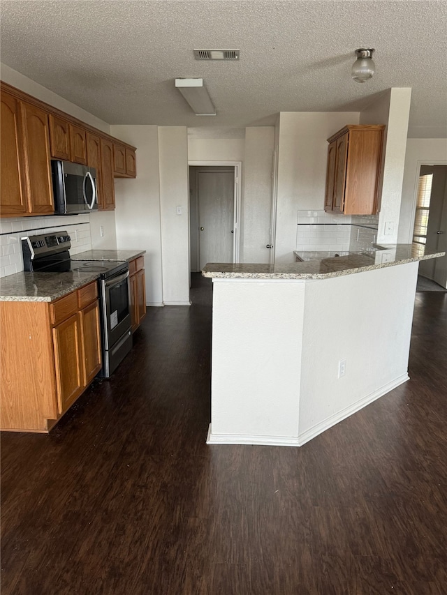 kitchen featuring dark hardwood / wood-style floors, a textured ceiling, light stone counters, kitchen peninsula, and stainless steel appliances