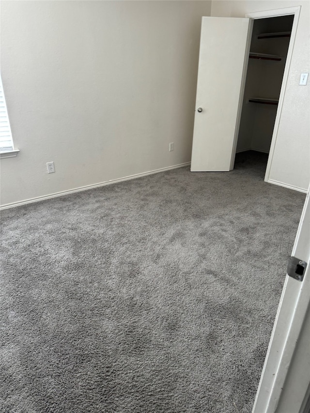 unfurnished bedroom with dark colored carpet, a walk in closet, and a closet