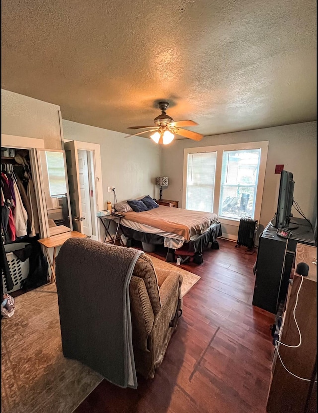 bedroom featuring dark hardwood / wood-style flooring, a textured ceiling, and ceiling fan