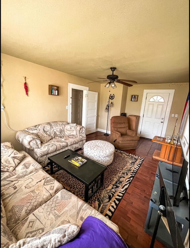 living room featuring ceiling fan, dark hardwood / wood-style floors, and a textured ceiling