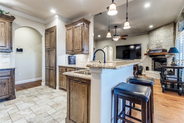 kitchen featuring kitchen peninsula, a kitchen breakfast bar, decorative backsplash, and light stone counters