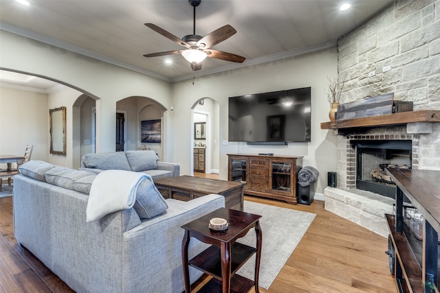 living room with a fireplace, hardwood / wood-style floors, ceiling fan, and ornamental molding