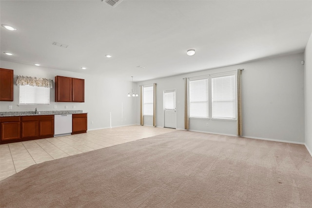 unfurnished living room with light carpet, an inviting chandelier, and sink