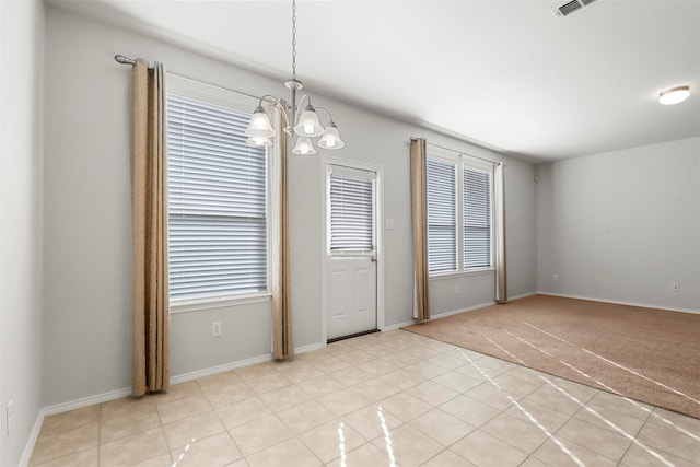 tiled spare room featuring plenty of natural light and a notable chandelier