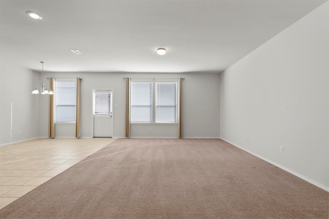 unfurnished room featuring a chandelier and light tile patterned flooring