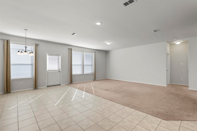 carpeted spare room with a chandelier