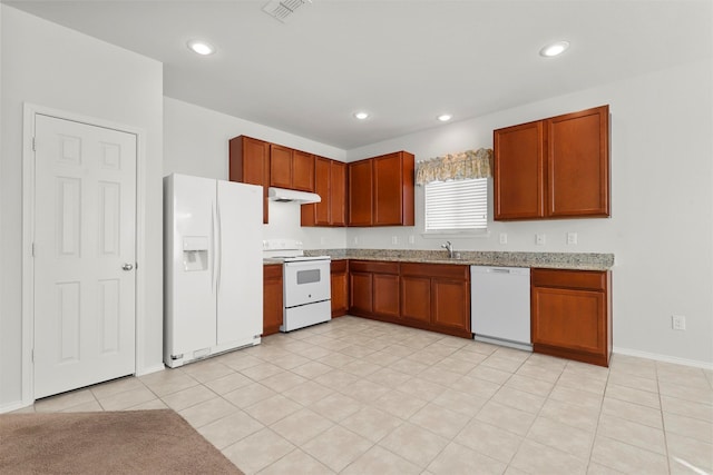 kitchen with light stone counters, white appliances, light tile patterned flooring, and sink