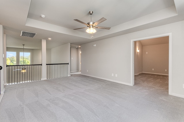 carpeted spare room featuring ceiling fan and a raised ceiling