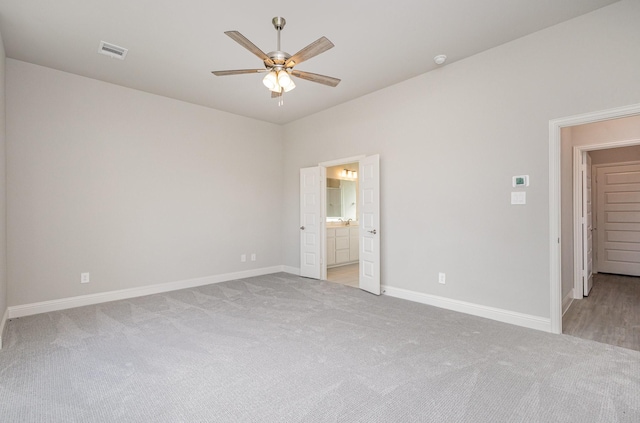 unfurnished bedroom featuring light colored carpet, ceiling fan, and ensuite bathroom