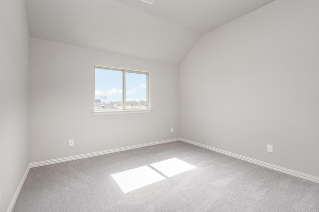 spare room with carpet and vaulted ceiling