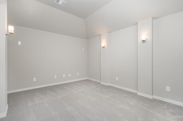 carpeted spare room featuring vaulted ceiling