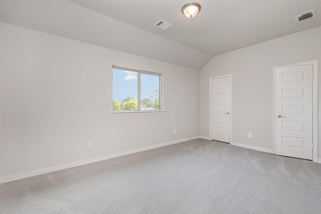 carpeted spare room featuring vaulted ceiling