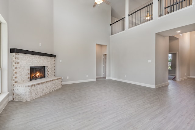 unfurnished living room featuring a towering ceiling, ceiling fan, and hardwood / wood-style flooring