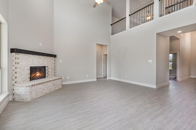 unfurnished living room featuring a towering ceiling, ceiling fan, and hardwood / wood-style flooring