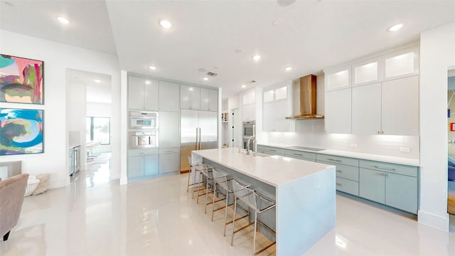 kitchen with tasteful backsplash, white cabinetry, wall chimney exhaust hood, and appliances with stainless steel finishes