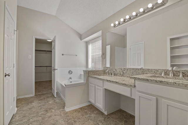 bathroom with vanity, lofted ceiling, a textured ceiling, and a bathing tub