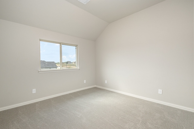 carpeted spare room with vaulted ceiling