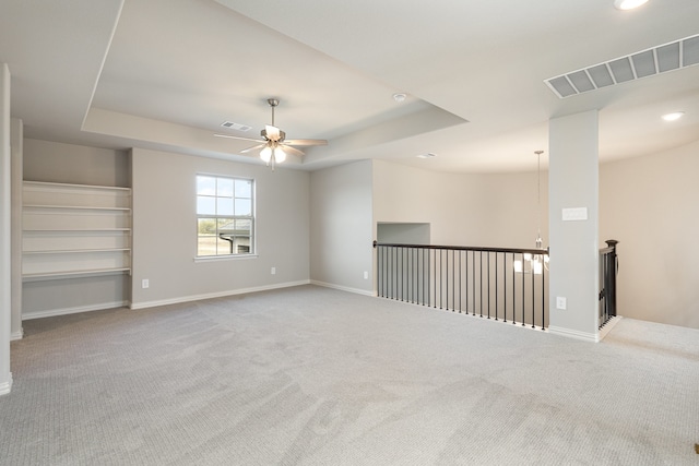 carpeted empty room with ceiling fan and a tray ceiling