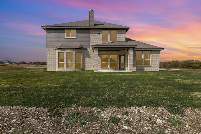 back house at dusk featuring a yard