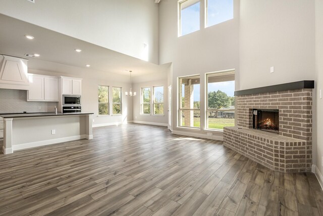 750 Serenity Ln, Red Oak, TX 75154 - unfurnished living room with a brick fireplace, plenty of natural light, dark wood-style flooring, a sink, and recessed lighting