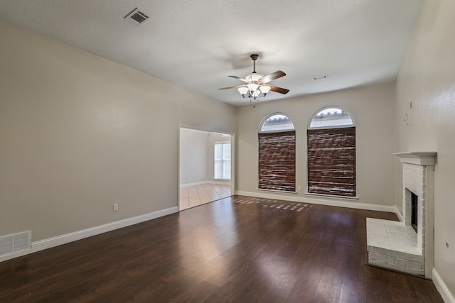 unfurnished living room with a textured ceiling, wood-type flooring, ceiling fan, and a fireplace