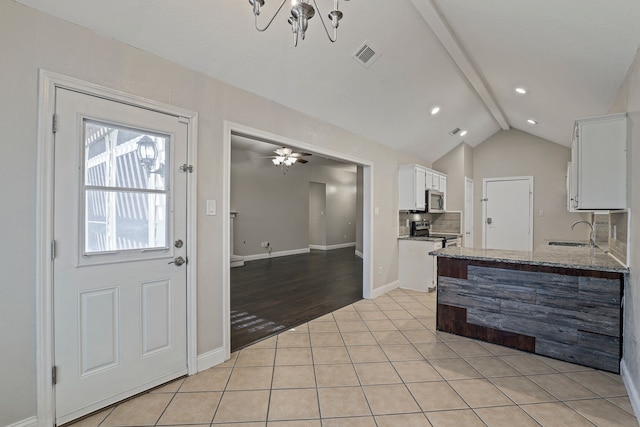 kitchen with white cabinetry, appliances with stainless steel finishes, stone counters, vaulted ceiling with beams, and light wood-type flooring