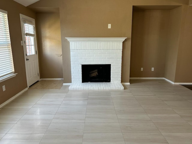 unfurnished living room with a brick fireplace and light tile patterned flooring