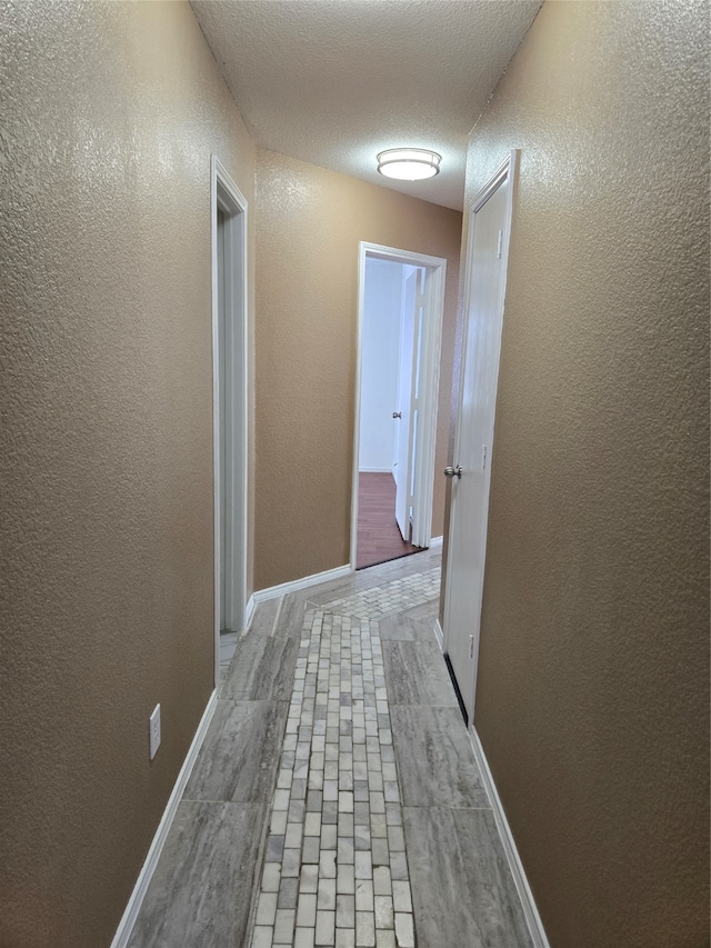 hallway with a textured ceiling and light hardwood / wood-style floors