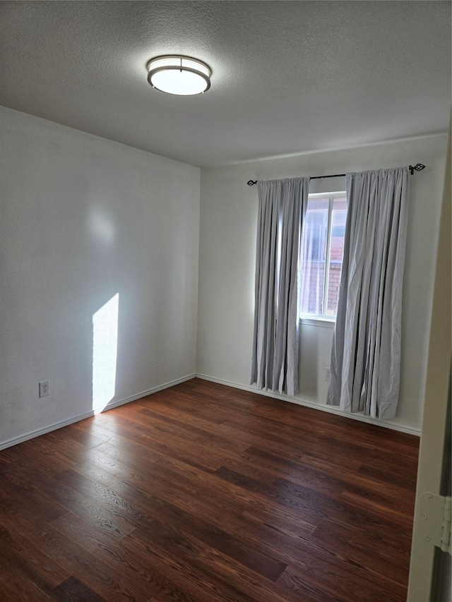 unfurnished room with dark wood-type flooring and a textured ceiling