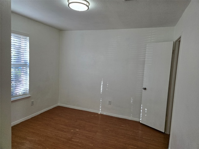 empty room featuring a textured ceiling and dark hardwood / wood-style floors