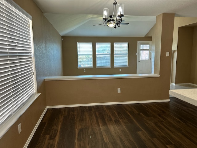 unfurnished room featuring dark hardwood / wood-style floors, a chandelier, and lofted ceiling