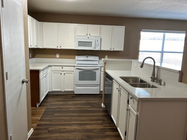 kitchen with white cabinetry, sink, light stone countertops, dark hardwood / wood-style floors, and white appliances