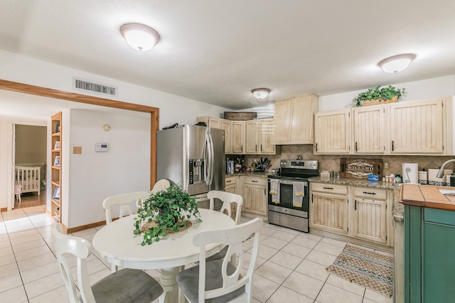 kitchen with backsplash, light brown cabinets, light tile patterned floors, and stainless steel appliances