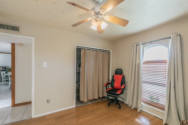 home office with light hardwood / wood-style floors and ceiling fan