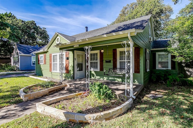 2309 Honeysuckle Ave, Fort Worth, TX 76111 - bungalow-style house with covered porch, a shingled roof, and a front lawn