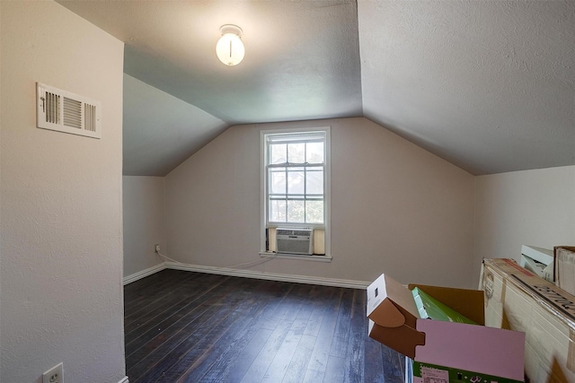 additional living space featuring cooling unit, dark wood-type flooring, a textured ceiling, and vaulted ceiling