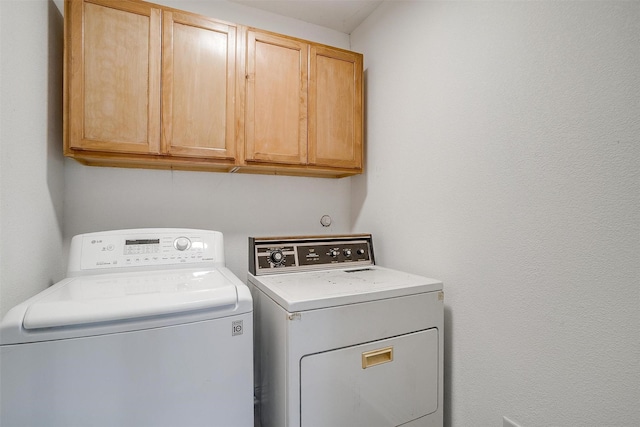 clothes washing area with independent washer and dryer and cabinets