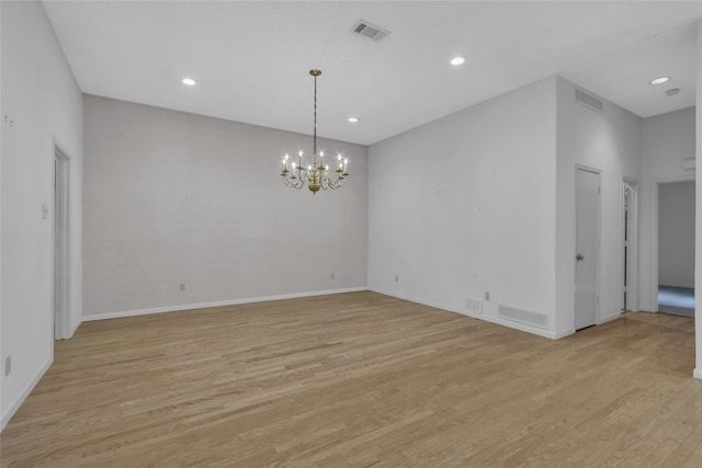 spare room with a notable chandelier, visible vents, light wood-style flooring, and recessed lighting