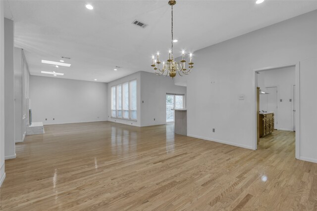 empty room with light wood-style flooring, baseboards, visible vents, and a chandelier