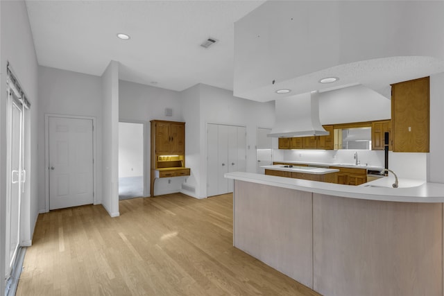 kitchen featuring visible vents, premium range hood, a sink, light countertops, and light wood-type flooring