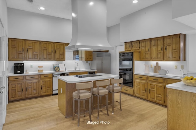 kitchen with island exhaust hood, high vaulted ceiling, black appliances, and a sink