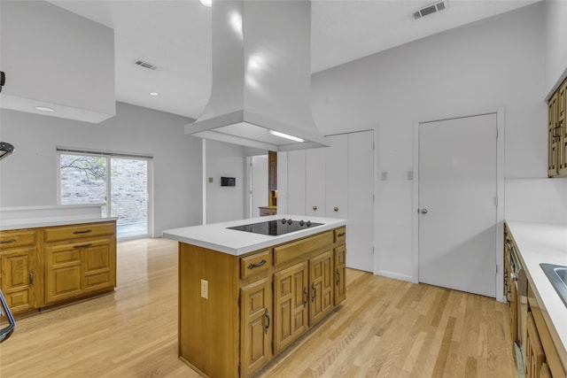 kitchen featuring black electric cooktop, visible vents, light wood finished floors, and island range hood