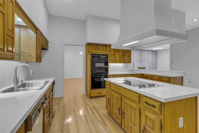 kitchen with custom exhaust hood, a sink, light countertops, black appliances, and light wood-style floors