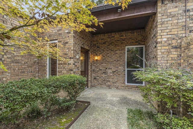 property entrance featuring brick siding and a patio