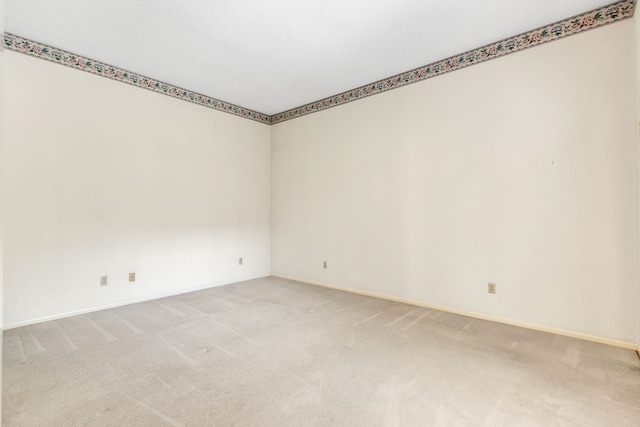 empty room featuring light carpet and baseboards