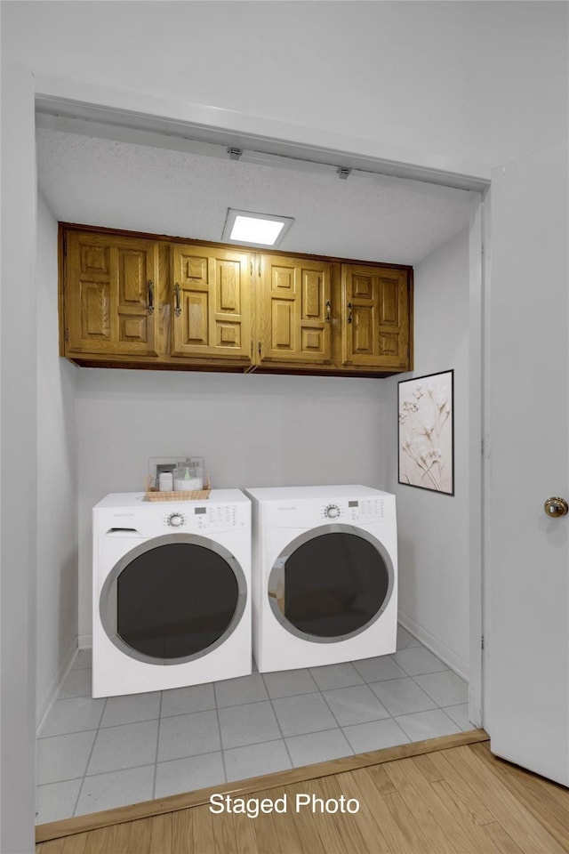 clothes washing area featuring cabinet space, light wood-style flooring, baseboards, and separate washer and dryer