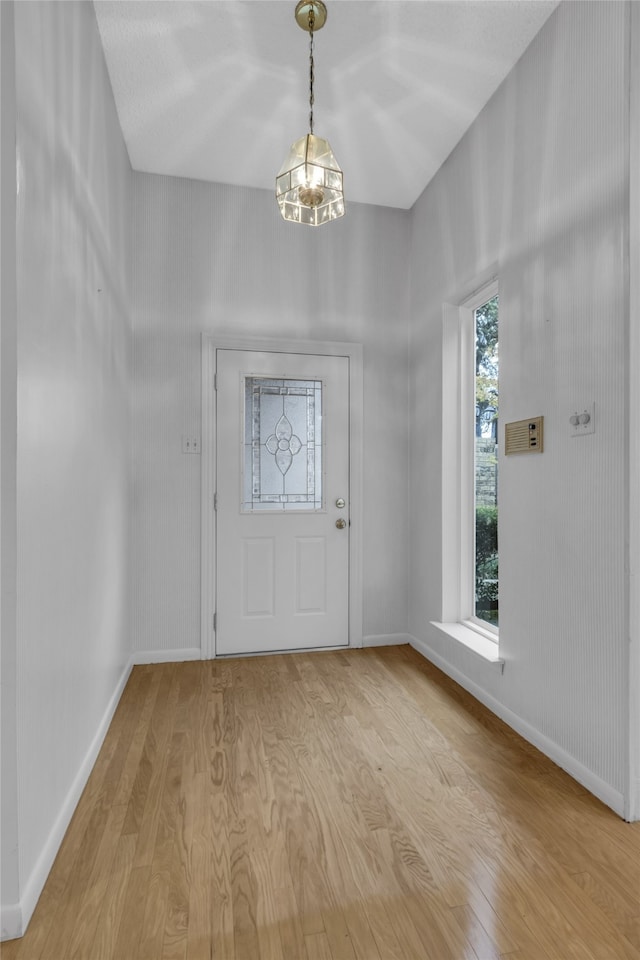 entryway featuring light wood finished floors, a chandelier, and baseboards