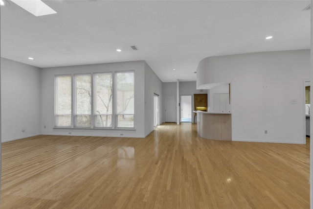 unfurnished living room featuring visible vents, baseboards, recessed lighting, light wood-style flooring, and a skylight